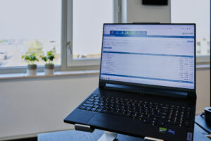 Een laptop waarvan de administratie in Conscribo te zien is met een raam en plantjes op de achtergrond.